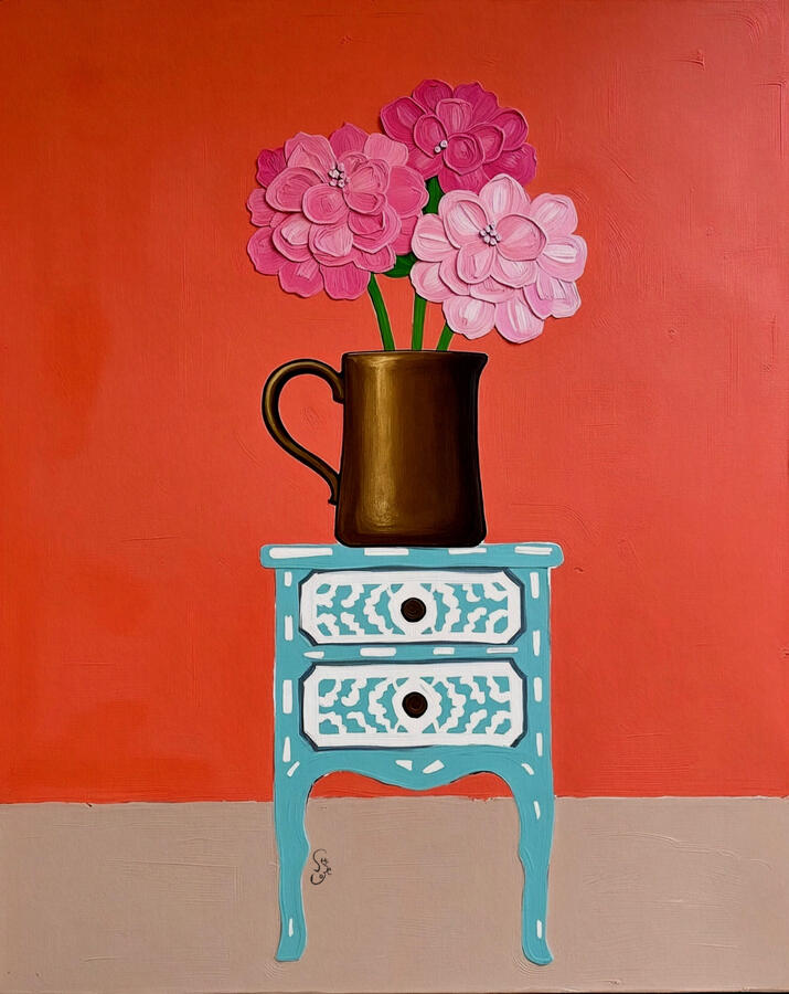Mixed pink hydrangea flowers in a bronze jar sitting atop a white patterned pale blue inlaid cabinet. Bright guava background.