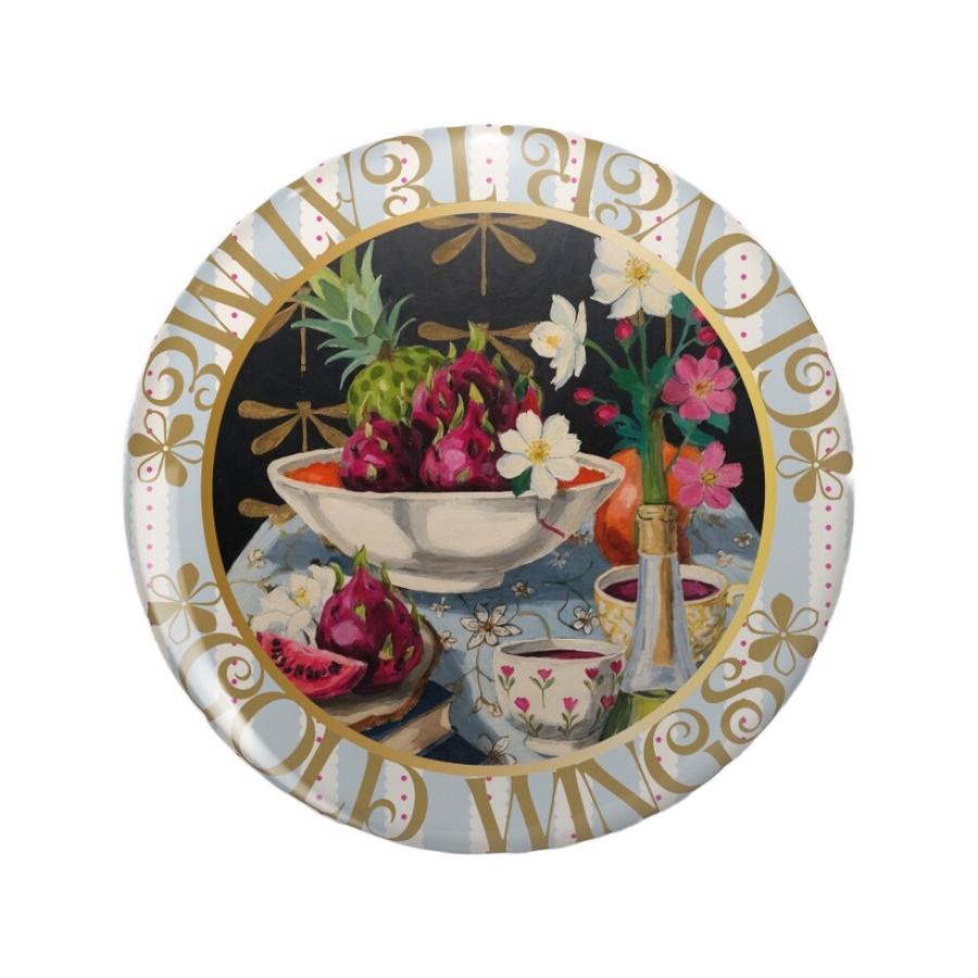 An ornate round pink back button close up, containing an illustration of A dark, moody still life painting of a tea table with white flowers in a green bottle, dragonfruit in a white bowl, and old books, set against a golden dragonfly patterned deep black
