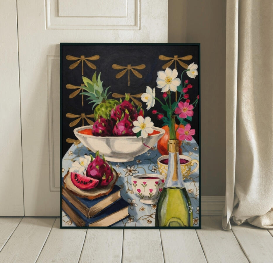 A black sleek picture frame resting on cream wooden floor, containing an illustration of A dark, moody still life painting of a tea table with white flowers in a green bottle, dragonfruit in a white bowl, and old books, set against a golden dragonfly patte