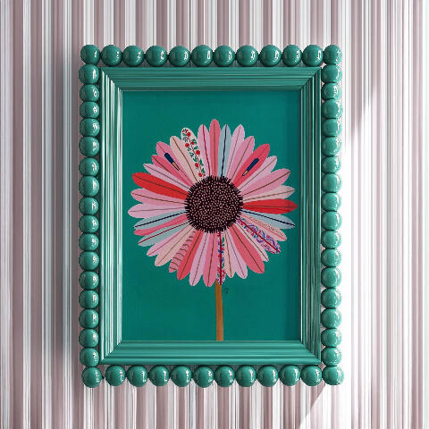 Acrylic art of a large stylized daisy with swirling petal patterns, vibrant pink and yellow core, surreal floral illustration, thick oil paint strokes. Framed in teal green bubble beaded maximalist frame on dove grey striped wall.