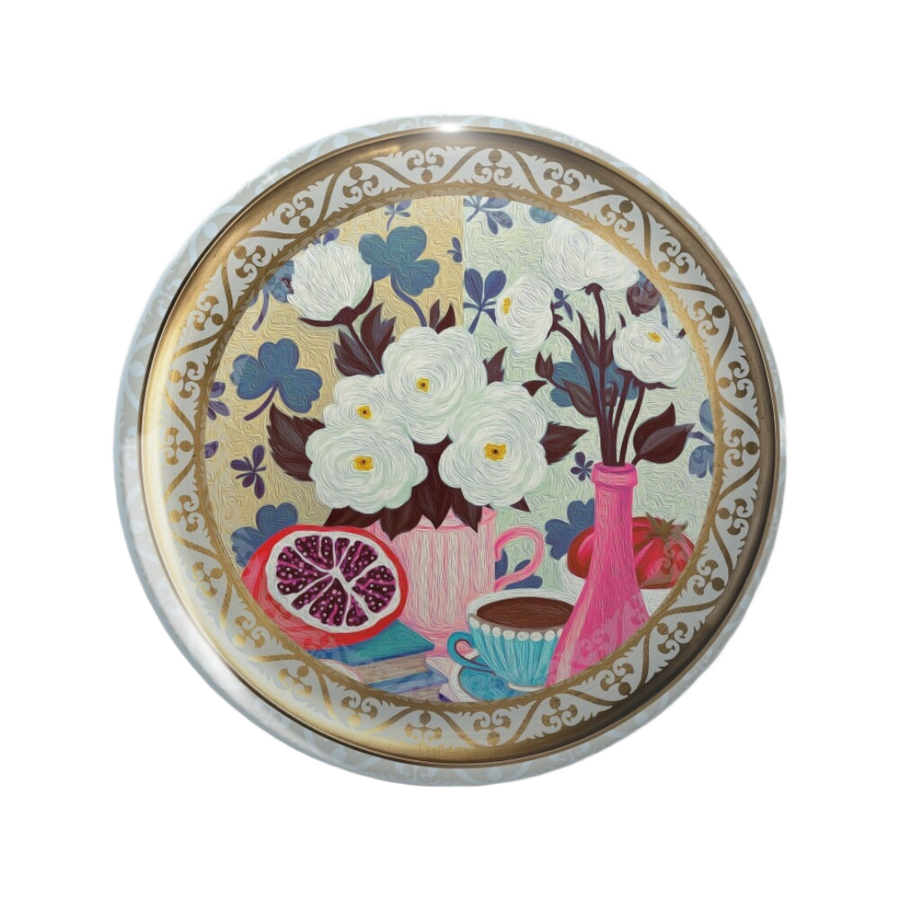 An ornate round pinback button close up, containing a a colorful still life painting with white flowers, clover leaves, books, fruit, and a pink bottle.