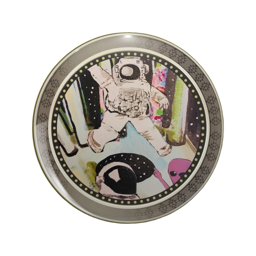 An ornate round pinback button close up, containing an illustration of an astronaut holding a spray can, a small pink alien, black starry shapes, and a floating bottle-like object.
